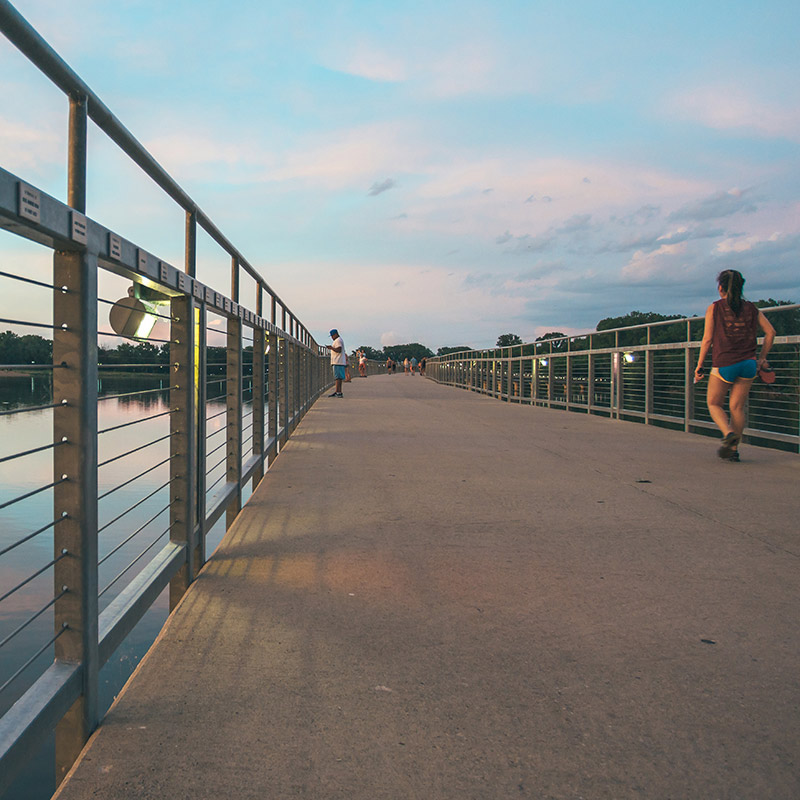 ϱ student walking on the pedestrian bridge over Raccoon River near downtown Des Moines